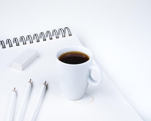 A cup of coffee and a notebook on a clean desk