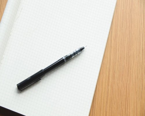 A notebook and pen on a desk ready for taking notes